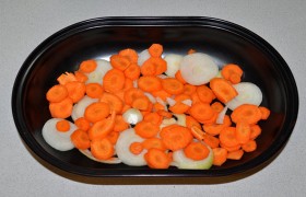 Чистим и нарезаем лук и морковь, засыпаем на дно формы, вливаем 2-3 ст. ложки воды и укладываем сверху окорок. 