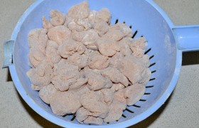 Перед обжариванием насыпаем в пакет муку, выкладываем в него кубики курицы, трясем, переворачиваем. Так мы получаем тонкую ровную  панировку  на мясе. И высыпаем кусочки в дуршлаг, в дырочки которого ссыпается лишняя мука. 