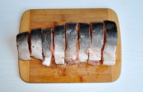 Тушку рыбы размораживаем на нижней полке холодильника, окончательно – на столе, лишаем чешуи, плавников, головы. Под струей воды хорошо промываем, снаружи и внутри протираем бумажными полотенцами. Остается тушка весом примерно 700 г, которую мы нарезаем стейками толщиной 20-25 мм.