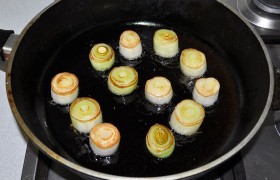 Белую нижнюю часть стебля лука-порея нарезаем по 20-25 мм. 2-3 ст. ложки масла разогреваем и на огне немного больше среднего подрумяниваем кругляши лука. Вынимаем.