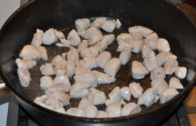Куриные филе промываем, обязательно – это важно для обжарки – обсушиваем в бумажных полотенцах и нарезаем кубиком до 20 мм. В  перекаленное  на сковороде масло выкладываем мясо и при постоянном помешивании жарим 2,5-3 минутки, пока всё оно побелеет. 