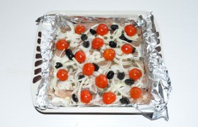 На рыбу выкладываем луковые полукольца или кольца, половинки  маслин , промытые  каперсы  и нарезанные на половинки или колечки черри, чеснок. Все это слегка присаливаем, перчим и щедро обрызгиваем маслом. Вторым листом фольги плотно «запечатываем» форму. 