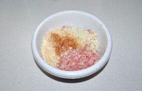 В миску с фаршем натираем кусок батона, посыпаем приправами, поливаем частью молока. Добавляем пропущенный через пресс чеснок и мелко порубленную луковицу. Вымешиваем, подливая по мере необходимости молоко, отбиваем .