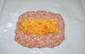 Берем пергамент, смазываем маслом, выкладываем фарш, разминаем в лепешку. По середине выкладываем морковь.