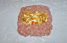 Фарш делим на 2 части, из которых, выложив на пленку, делаем прямоугольные лепешки. На середину каждой кладем начинку.