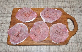 Кусок мяса обязательно промываем и в бумажных полотенцах подсушиваем – это важно для жарки. Срезаем лишний слой жира (если есть). Нарезаем (поперек волокон) отбивные до 15 мм толщины,  отбиваем  в пакетике, который помогает избежать брызг и повреждения мяса. Приправляем перцем и солью. 