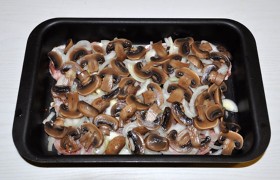 Выкладываем мясо в форму, промазанную растительным маслом, засыпаем довольно тонкими полукольцами лука. Сверху раскладываем промытые и нарезанные ломтиками шампиньоны.