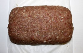 С помощью бумаги поднимаем края, очень тщательно заделываем шов рулета, закрываем его фаршем по краям.