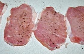 Свинину поперек волокон нарезаем ломтями около 1,5 см толщиной,  отбиваем  через пленку (не будет брызг) до толщины примерно 1 см. Посыпаем или натираем солью и перцем. Заодно нарезаем кружки помидоров и натираем сыр.