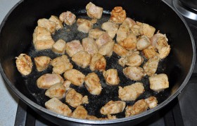 Тут уже  перекалилось  масло в сковороде - ее мы 4-5 мин. назад поставили на сильный огонь. Кладем половину куриного мяса – чтобы жарилось быстро, и сок остался внутри. Через 40-45 секунд переворачиваем, помешиваем еще около минуты. Обжаренные кубики филе убираем и жарим вторую половину. 