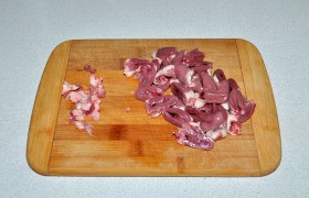 Сердечки разрезаем пополам вдоль, отсекая остатки сосудов и лишний жир. Тщательно промываем до чистой воды, удаляя из серединки сгустки крови.