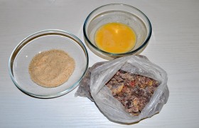 Берем пакет, засыпаем муку, закладываем сердечки, «выгоняем» воздух, крепко держа в руке, потряхиваем и поворачиваем пакет, пока все сердечки запанируются в муке. Выкладываем на тарелку. Ставим емкости с взбитыми яйцами (с небольшой добавкой молока или воды) и панировочными сухарями.