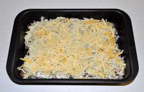 А сверху засыпаем слоем тертого крупно сыра. И запечатываем верх фольгой. Ставим на средний уровень духовки.