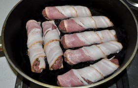 Когда снизу бекон подрумянился – убираем огонь до почти среднего. Жарим колбаски в общей сложности 18-20 минут, поворачивая с боку на бок, подрумянивая со всех сторон.