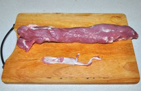 После промывания и обсушивания мяса острым небольшим ножом терпеливо срезаем с вырезки имеющиеся белые пленки. Если филе мы купили с тонким мясным «хвостиком» на его конце – стоит согнуть его и закрепить.