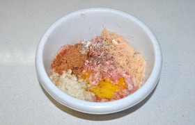 В миску с фаршем добавляем натертый и отжатый от жидкости кабачок или картофелины. А еще – готовую приправу, перец и соль, яйцо. И половину луковицы, порубленной мелко. Руками вымешиваем, в результате он становится довольно густым. Если фарш жидковат – добавляем горсть овсяных хлопьев или панировочных сухарей. В конце недолго  отбиваем фарш  – 12-14 раз.