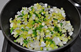 Огонь конфорки переводим на средний. Кладем имбирь и чеснок, через 30-40 секунд высыпаем лук-порей и лук зеленый.